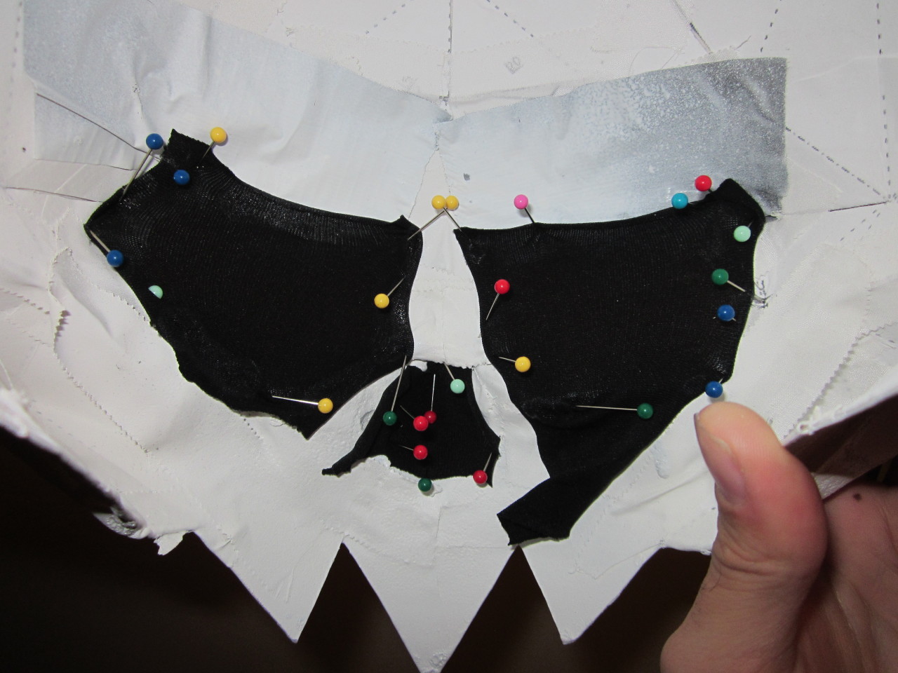 The inside of the skull, showing the eye and nose holes covered by black fabric pinned in place with colorful sewing pins.