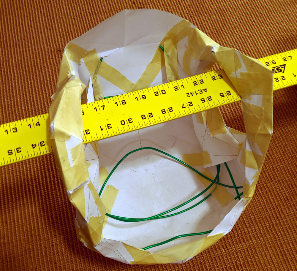 Suspended from a large ruler, the paper head contains green wire taped to its insides.